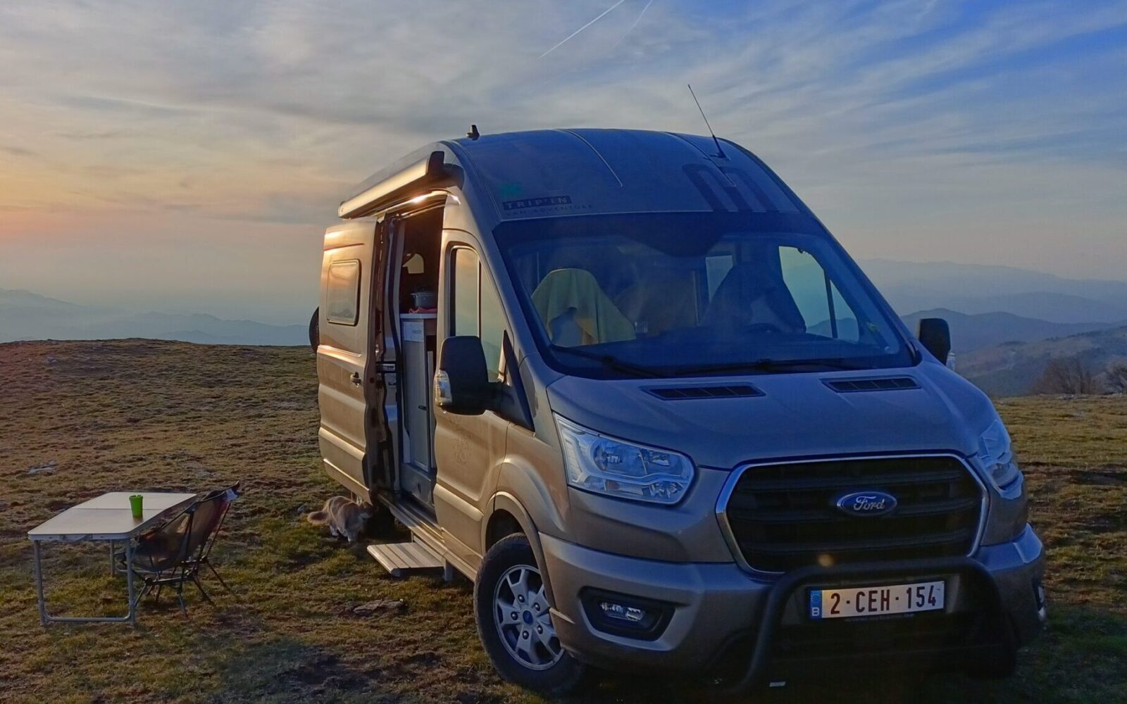 Van aménagé stationné au coucher du soleil dans un paysage pittoresque - Trip'in location de vans