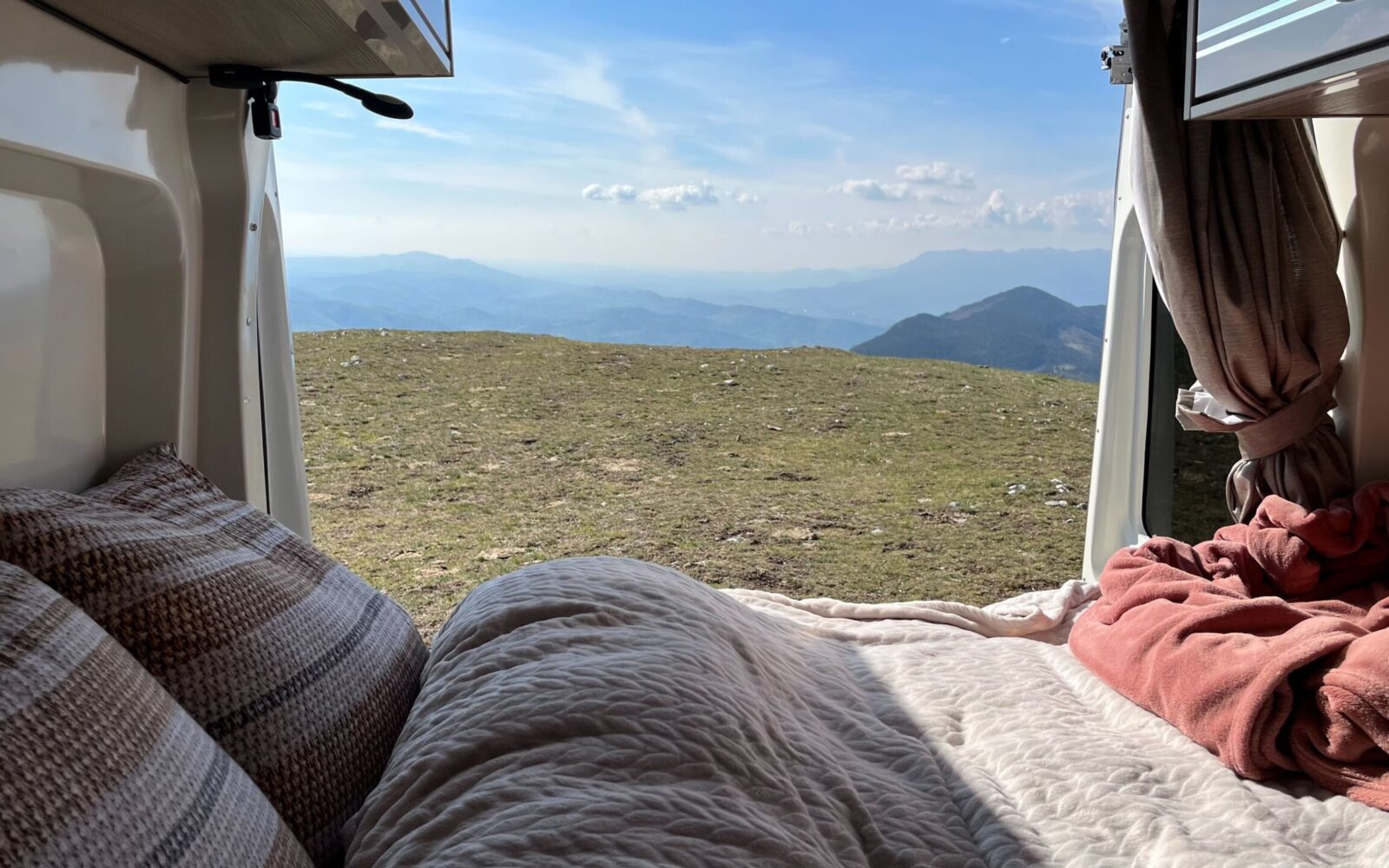 Vue panoramique des montagnes depuis l'intérieur du van aménagé - Trip'in location de vans