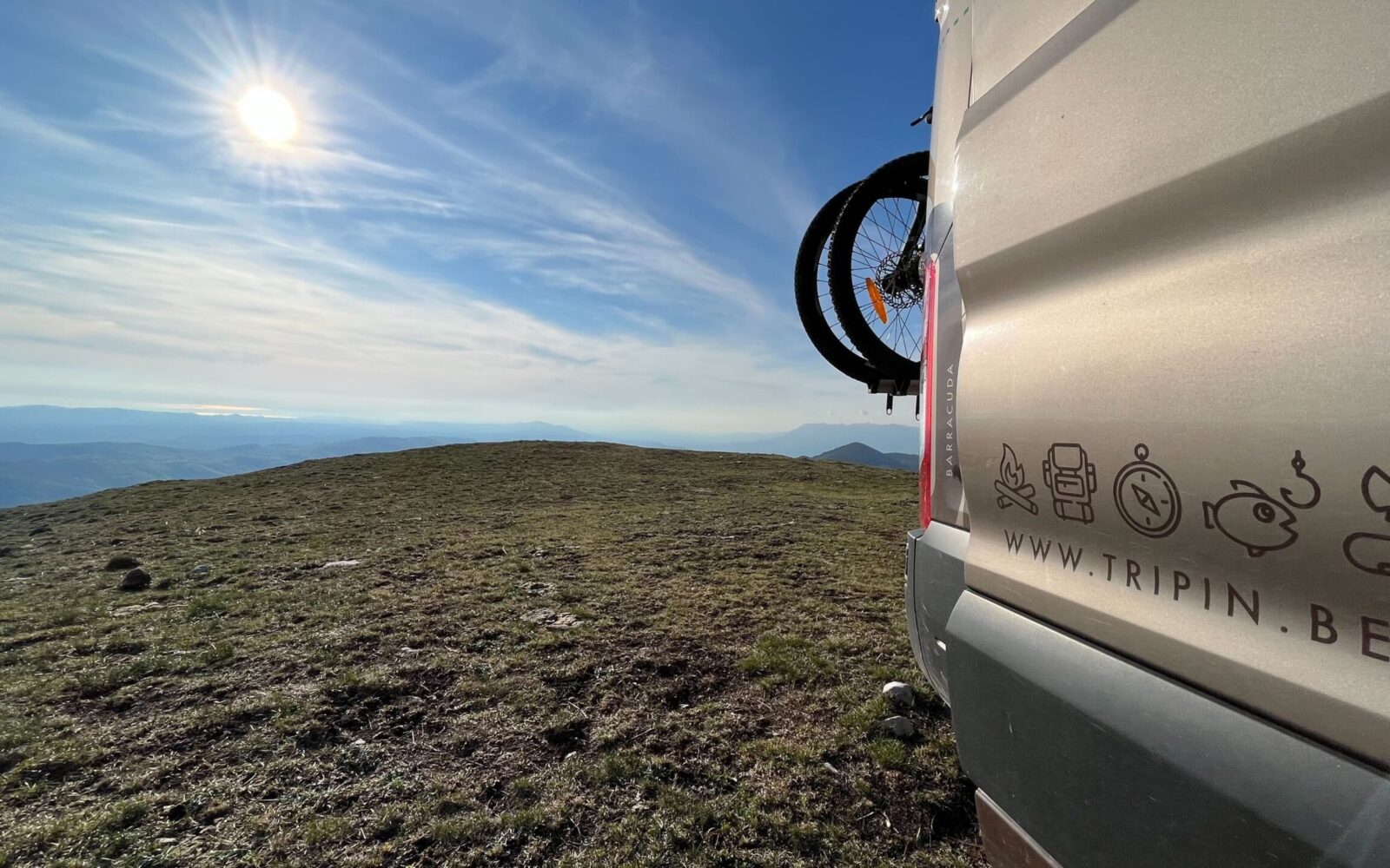 Van aménagé avec un vélo attaché et vue sur le paysage ensoleillé - Trip'in location de vans